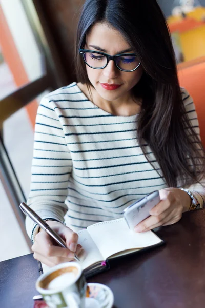 Jovem mulher bonita usando seu telefone celular no café . — Fotografia de Stock