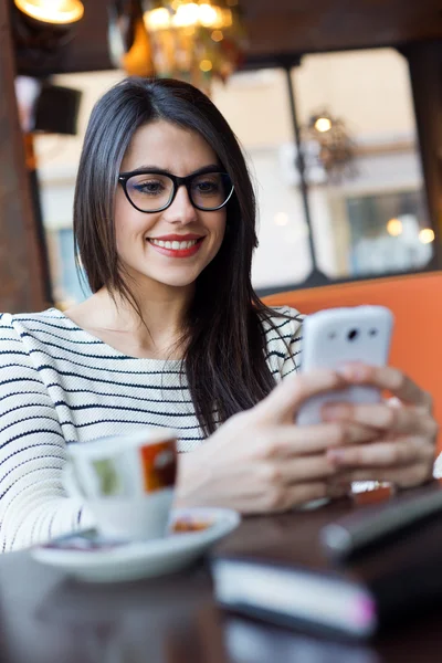 Молодая красивая женщина использует свой мобильный телефон в кофе . — стоковое фото