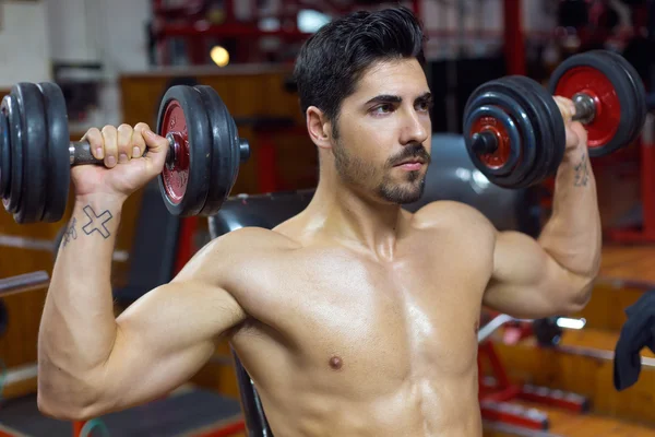 Hombre joven haciendo ejercicio de peso pesado en el gimnasio . — Foto de Stock