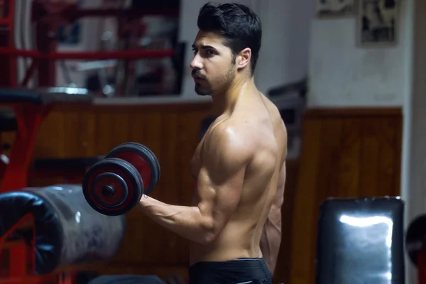 Hombre joven haciendo ejercicio de peso pesado en el gimnasio . — Foto de Stock