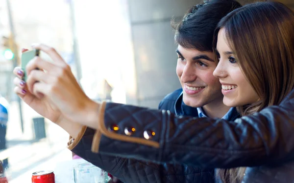 Ungt par med mobiltelefon i café. — Stockfoto