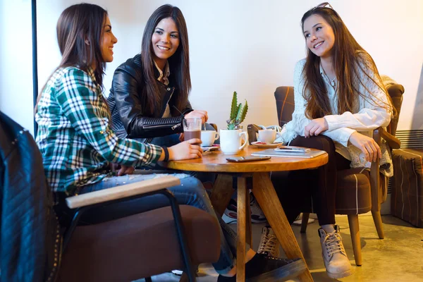 Três jovens bebendo café e falando na cafetaria . — Fotografia de Stock