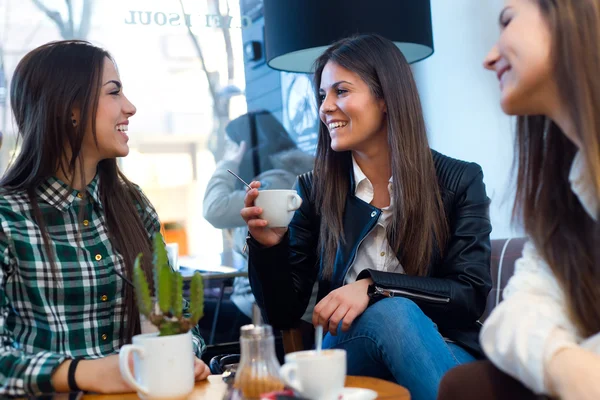 Tres mujeres jóvenes tomando café y hablando en la cafetería . — Foto de Stock