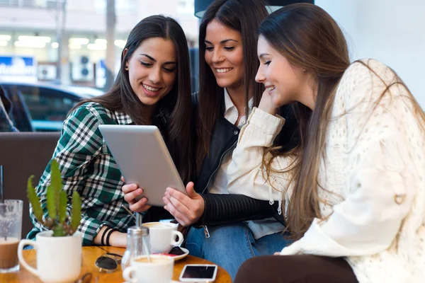 Tres mujeres jóvenes usando tableta digital en la cafetería . — Foto de Stock