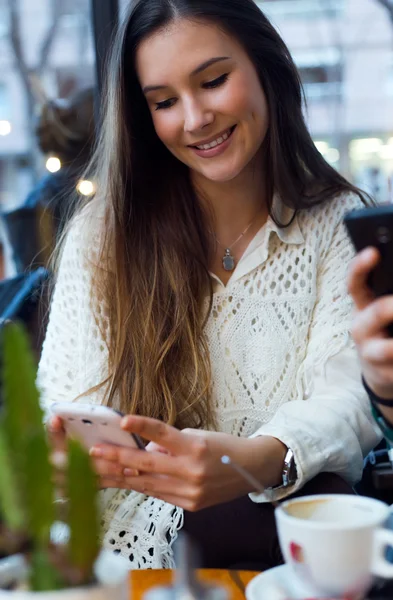 Mooie jonge vrouw met behulp van haar mobiele telefoon bij café shop. — Stockfoto
