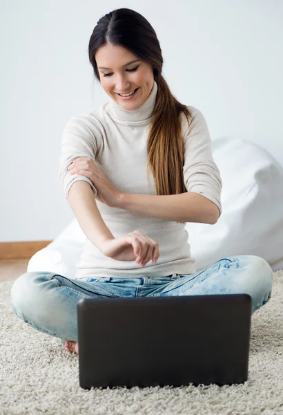 Vacker ung kvinna som arbetar på sin bärbara dator hemma. — Stockfoto