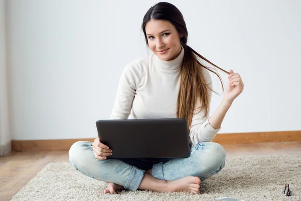 Schöne junge Frau arbeitet zu Hause an ihrem Laptop. — Stockfoto