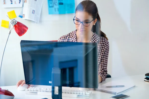 Hermosa mujer joven usando su computadora portátil en la oficina . — Foto de Stock