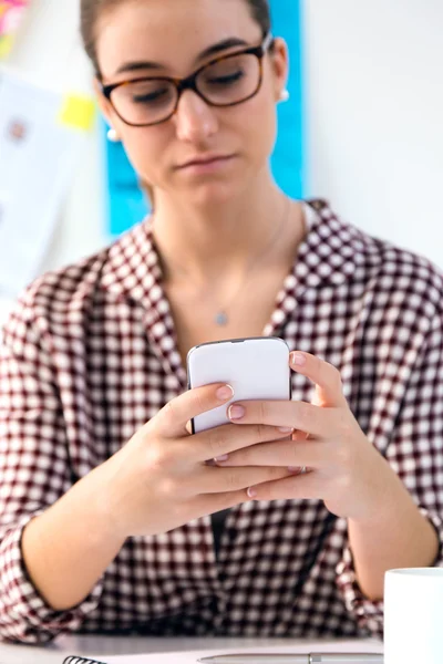 Krásná mladá žena pomocí její mobilní telefon v kanceláři. — Stock fotografie