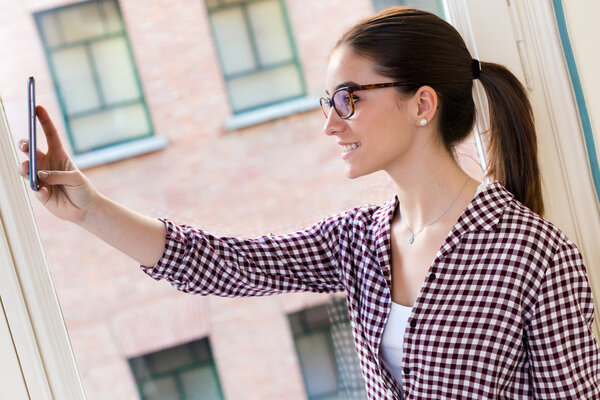 Beautiful young woman using her mobile phone in the office.