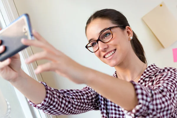 Hermosa mujer joven usando su teléfono móvil en la oficina . — Foto de Stock