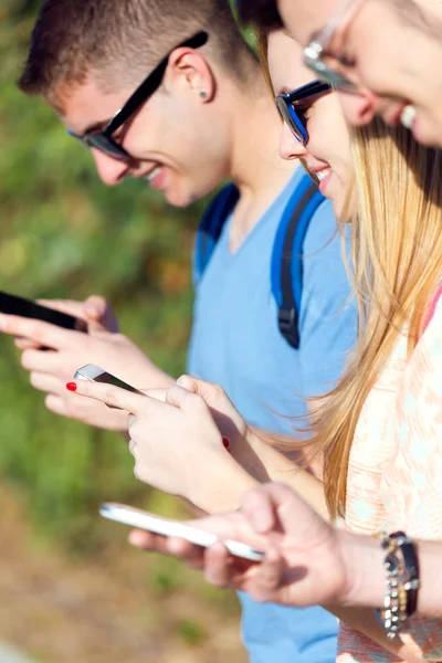 Un grupo de estudiantes divirtiéndose con teléfonos inteligentes después de clase . —  Fotos de Stock