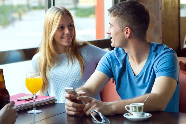 Groep vrienden met behulp van mobiele telefoon in café. — Stockfoto