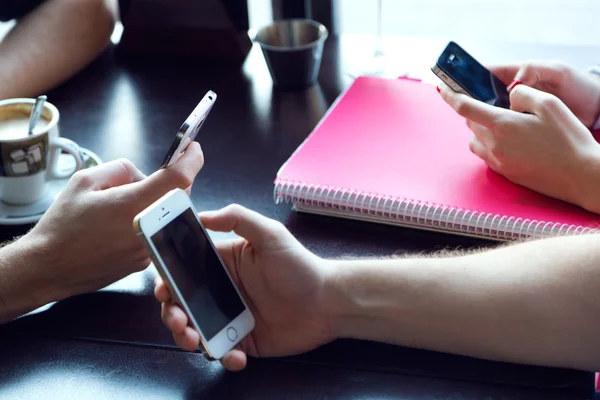 Group of friends using mobile phone in cafe. — Stock Photo, Image