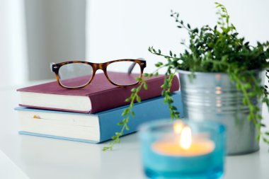 Kitap, gözlük ve mum gece masada.