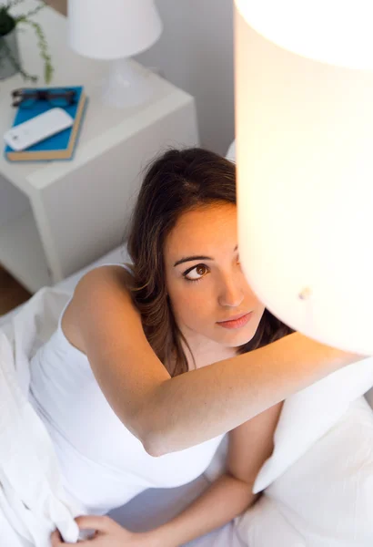 Mooie jonge vrouw het uitschakelen van de lamp. — Stockfoto