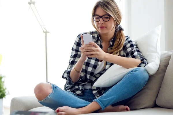 Krásná mladá žena pomocí svého mobilního telefonu doma. — Stock fotografie