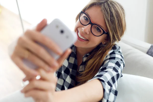 Beautiful young woman using her mobile phone at home. — Stock Photo, Image