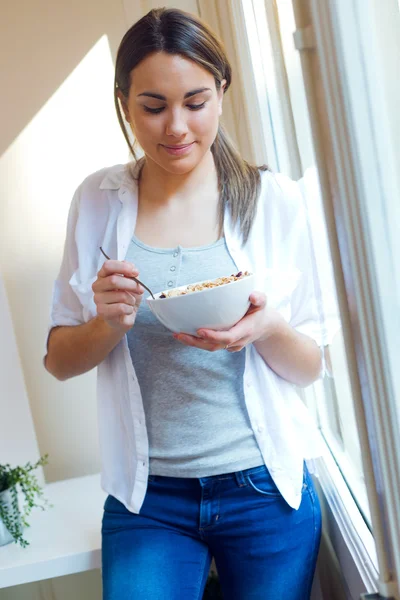 Mooie jonge vrouw eten granen thuis. — Stockfoto