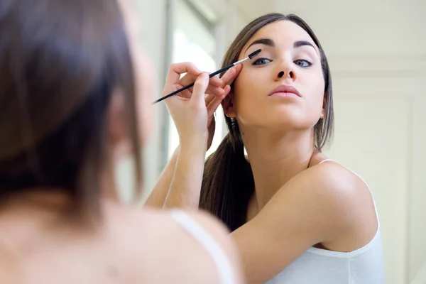 Vacker ung kvinna att göra make-up nära spegel. — Stockfoto