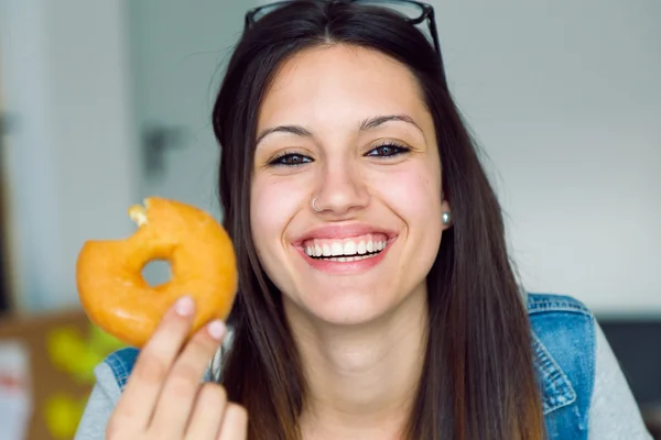 Güzel genç kadın evde donut yemek. — Stok fotoğraf