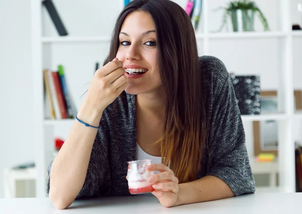 Beautiful young woman eating yogurt at home. — Stock Photo, Image