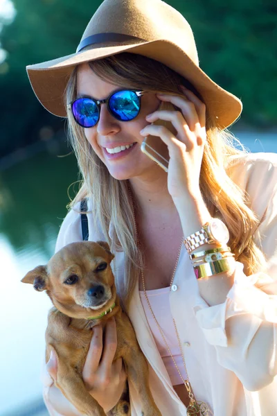 Beautiful young woman with her dog using mobile phone. — Stock Photo, Image