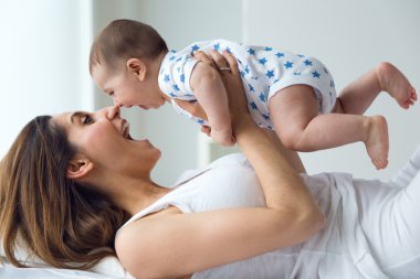 Anne ve bebek oynama ve evde gülümseyen.