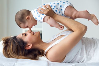 Anne ve bebek oynama ve evde gülümseyen.