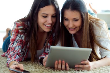 Dijital kullanarak iki güzel genç kadın arkadaş evde tablet.
