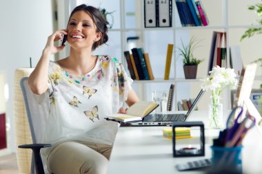 Ofiste cep telefonu kullanan genç ve güzel kadın.