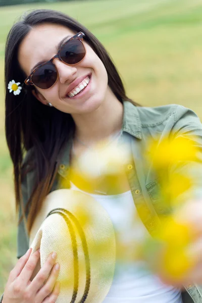 Vacker ung kvinna tittar på kameran med blommor. — Stockfoto