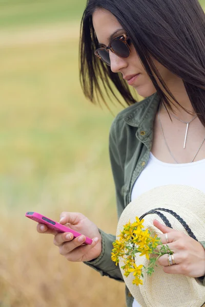 Красивая молодая женщина использует свой мобильный телефон в парке . — стоковое фото