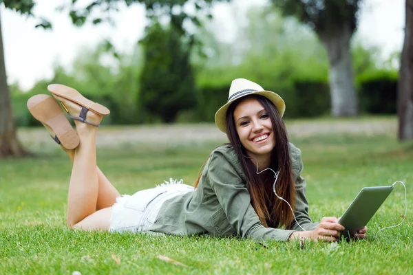 Mooie jonge vrouw met behulp van digitale tablet in het park. — Stockfoto