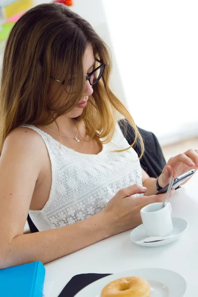 Hübsche junge Frau benutzt ihr Handy zu Hause. — Stockfoto