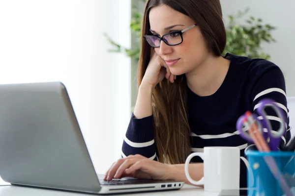 Vertrouwen jonge vrouw die in haar kantoor met een laptop werkt. — Stockfoto