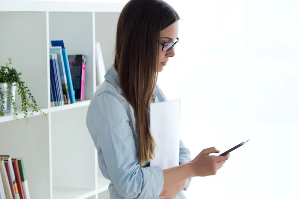 Selbstbewusste junge Frau arbeitet in ihrem Büro mit dem Handy. — Stockfoto