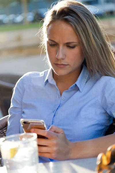 Hermosa mujer joven usando su teléfono móvil en un restaurante ter — Foto de Stock