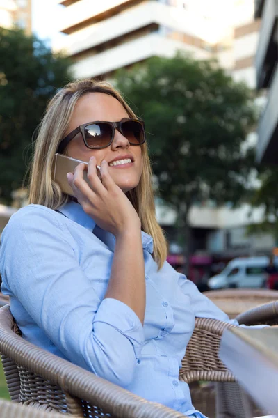 Hermosa mujer joven usando su teléfono móvil en un restaurante ter — Foto de Stock