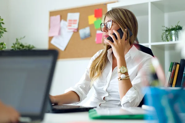 Femme d'affaires travaillant avec un téléphone portable dans son bureau . — Photo