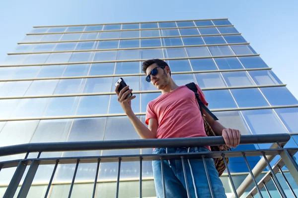 Bello giovane uomo che usa il suo cellulare per strada . — Foto Stock