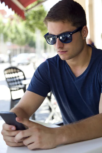 Knappe jongeman met behulp van zijn mobiele telefoon in de straat. — Stockfoto