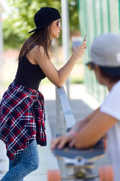 Two skaters using mobile phone in the street. — Stock Photo, Image