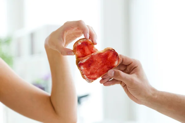 Paar macht Herzzeichen mit zwei Scheiben Brot mit Marmelade. — Stockfoto