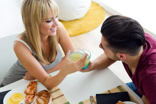 Glückliches junges Paar genießt das Frühstück in der Küche. — Stockfoto