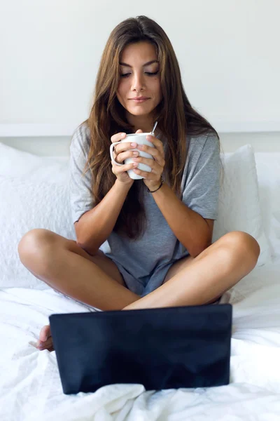 Hermosa mujer joven usando su portátil amb beber café en ho —  Fotos de Stock