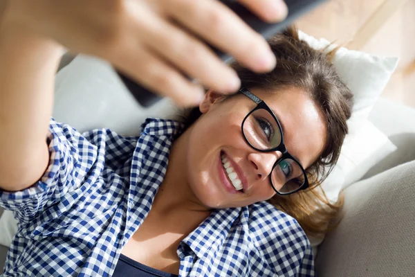 Vacker ung kvinna med en selfie i hemmet. — Stockfoto