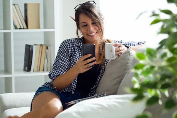 Vacker ung kvinna med hennes mobiltelefon hemma. — Stockfoto
