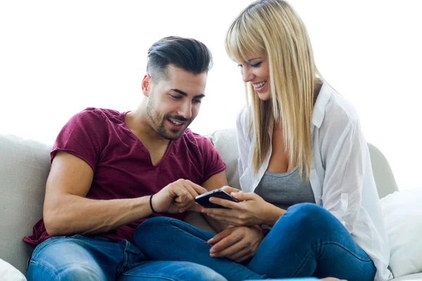 Belo jovem casal usando telefone celular em casa . — Fotografia de Stock