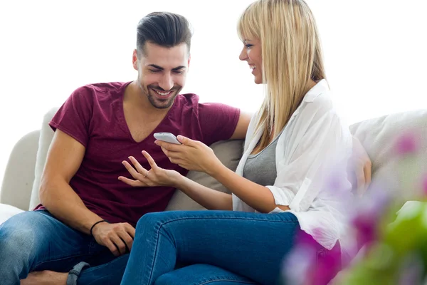 Belo jovem casal usando telefone celular em casa . — Fotografia de Stock